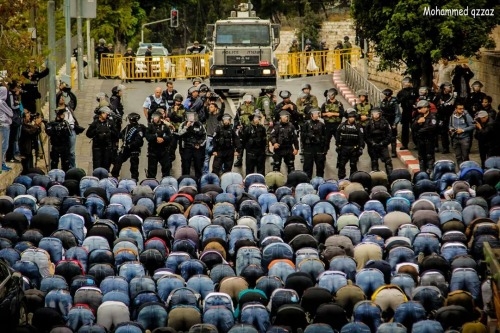 Palestinians pray in front of Israeli right police